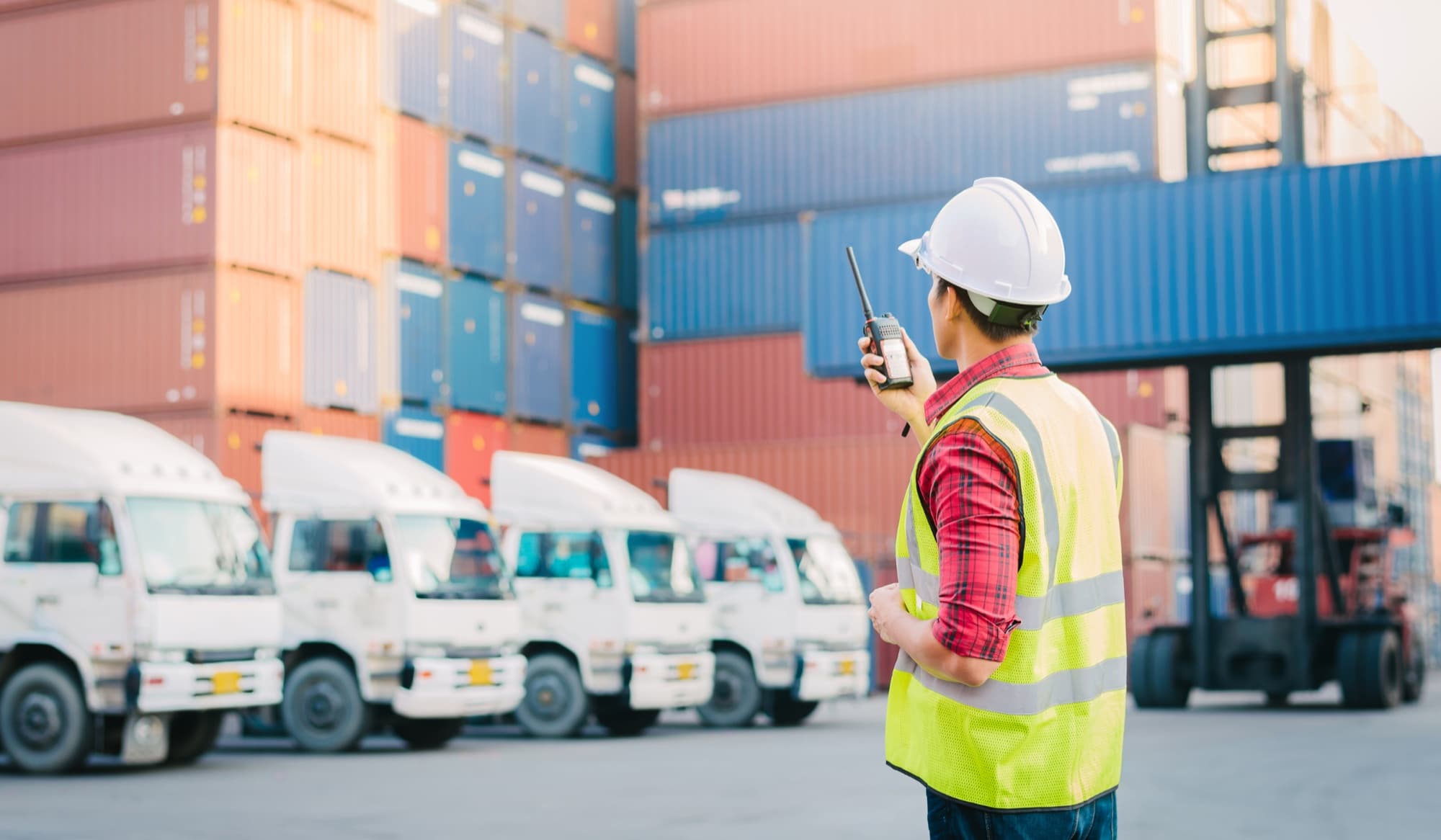 Logistics control tower operator coordinating trucks and containers at a freight yard