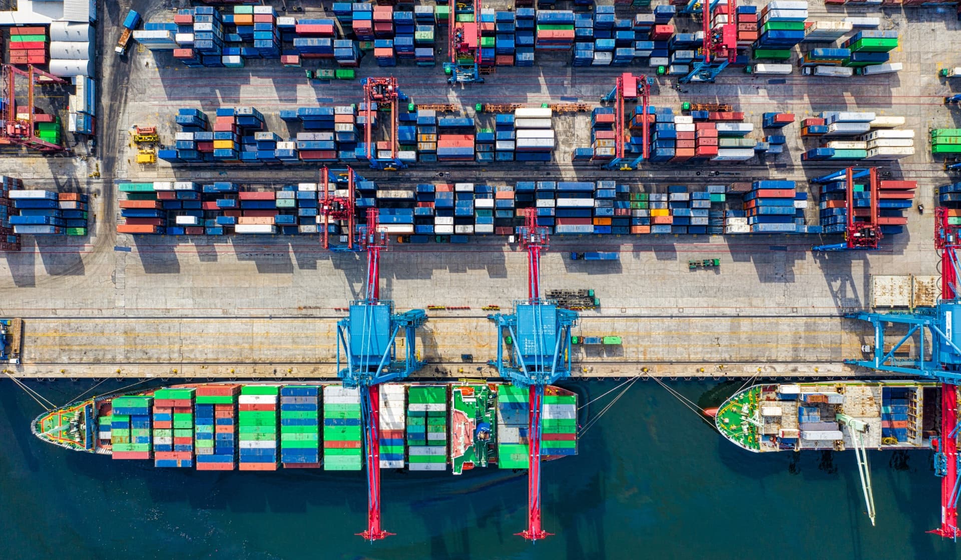 Aerial view of export containers, cranes, and cargo ships at a busy international port